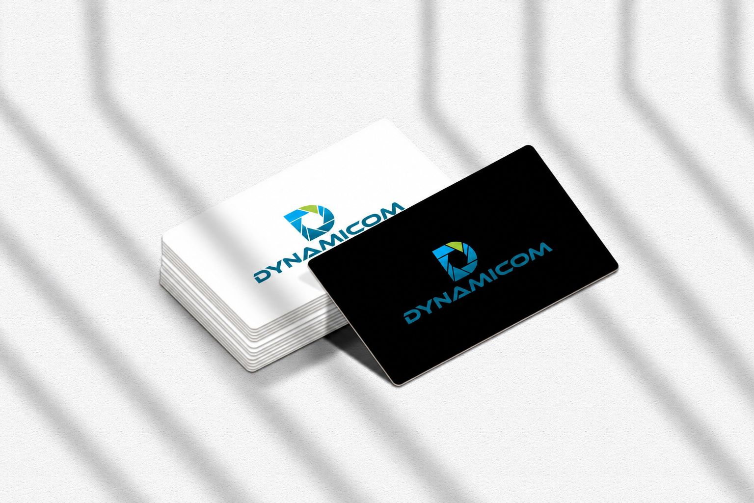 Cartes d'affaires Dynamicom, une noire et une pile de blanches, sur fond texturé clair