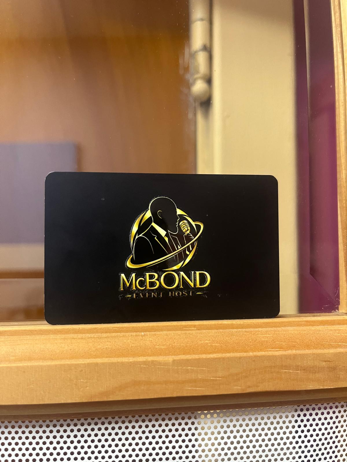 Carte NFC noire avec un logo d'hôte d'événement en or, posée sur un rebord de bois