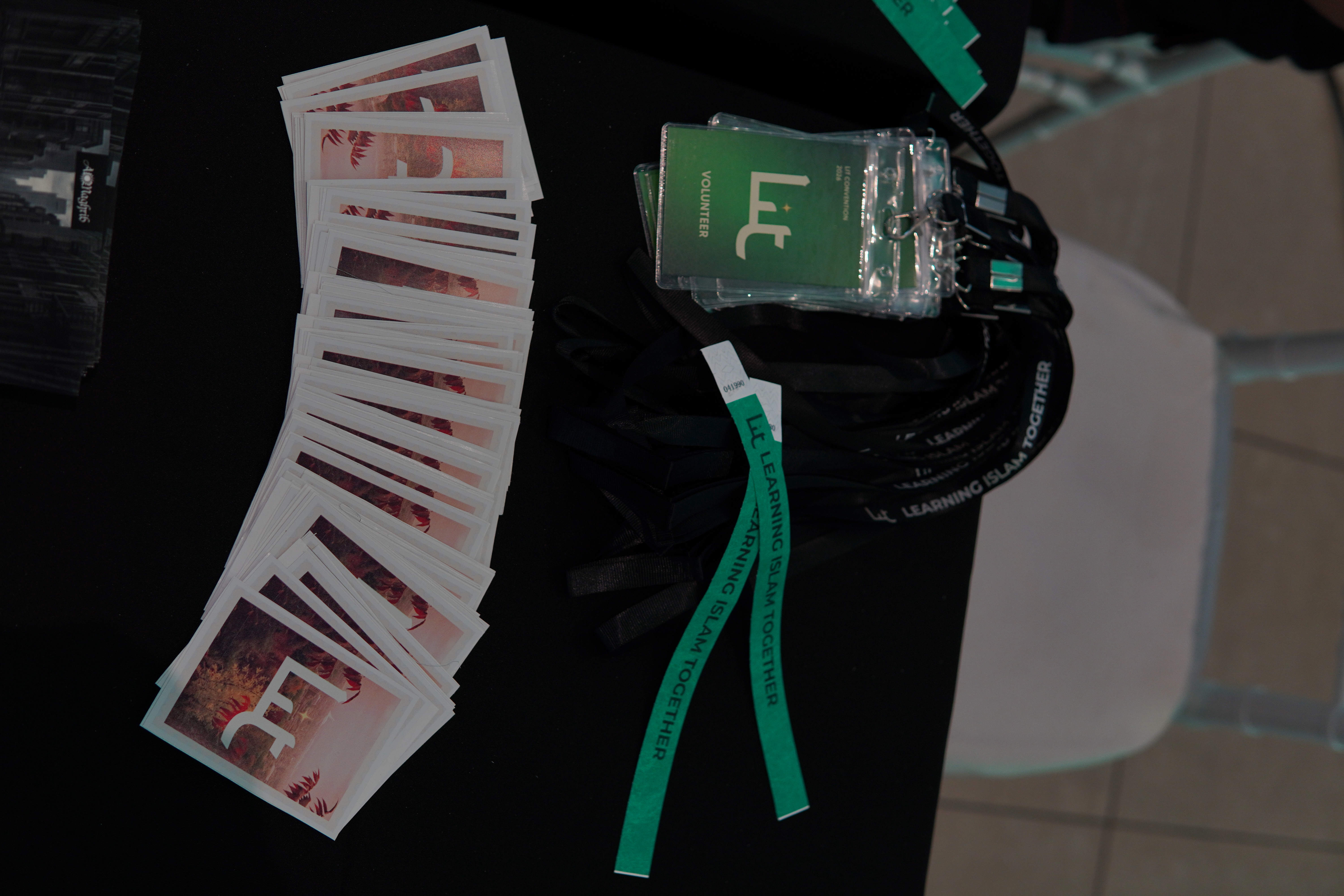 Cordons, badges de bénévoles, bracelets et cartes imprimées disposés sur une table d'inscription