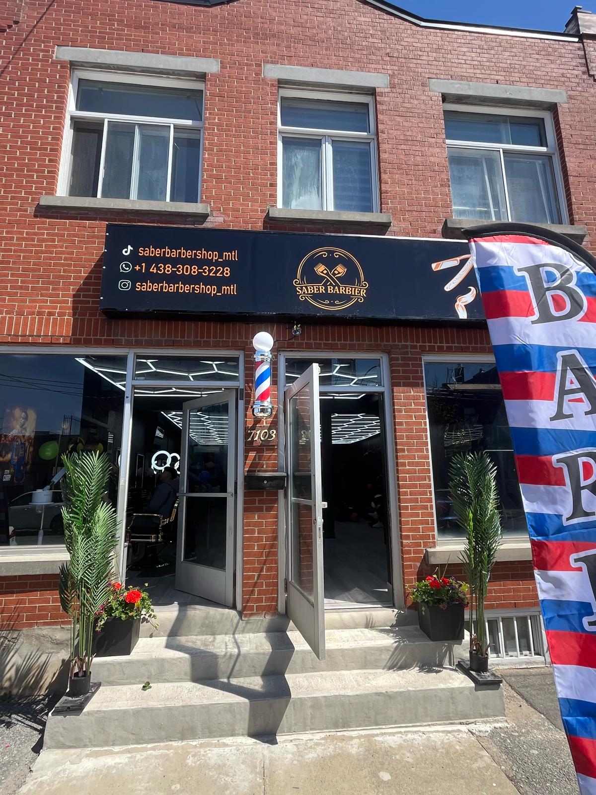 Enseigne de vitrine imprimée au-dessus de l'entrée d'un barbier, avec un drapeau plume à côté
